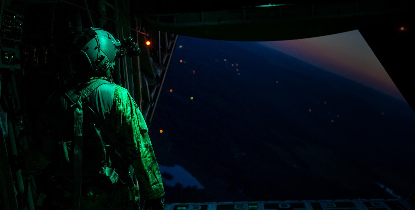 士兵戴着头戴式耳机，使用军用卫星通信，在夜间从飞机上往外看