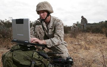 战场上的战士在移动中使用卫星通信在笔记本电脑上进行通信